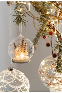 Close-up of LED glowing glass ornament with miniature reindeer and snow trees