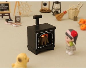 Macro shot of miniature black dollhouse fireplace with glowing wood and warm LED fire effect