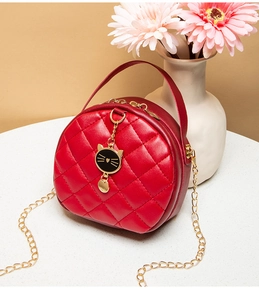 Detailed view of red quilted mini bag with gold cat pendant and metal chain strap