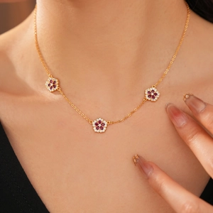 Dettaglio della collana floreale placcata oro 18K al collo con fiori di zirconia rossi e bianchi
