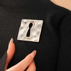 Detailed close-up of a silver vintage square brooch with a keyhole cutout and hammered texture