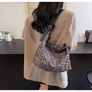 Leopard print tote bag shown on model's shoulder with adjustable leather strap