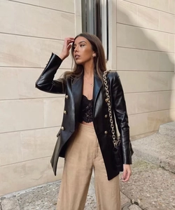 Detail of black PU leather blazer with gold double-breasted buttons and stylish texture