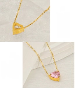 Detail of heart-shaped zircon pendants on stainless steel necklaces in pink and white colors