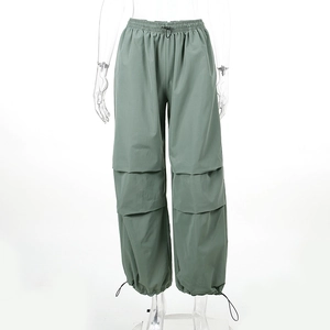 Dettaglio dei pantaloni cargo grigio-verde a vita alta con coulisse e design a strati