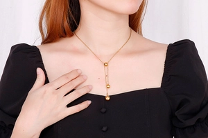 Golden Y-shaped necklace featuring three polished sphere pendants on a female model