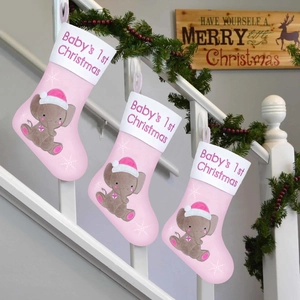 Drei rosa Baby-Weihnachtssocken mit Elefantenmotiv an einem weißen Treppengeländer