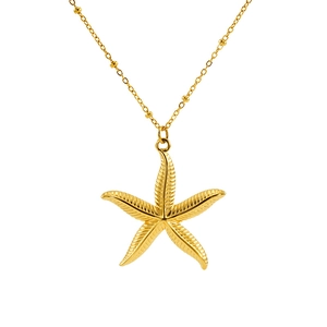 Macro shot of gold starfish pendant and beaded chain for vintage ocean jewelry set