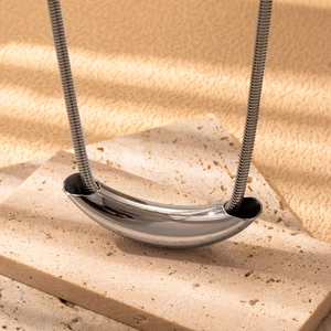 Minimalist silver stainless steel snake chain necklace with curved tube pendant on stone