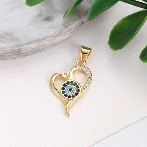 Detail of gold heart pendant with evil eye stones on a marble surface background
