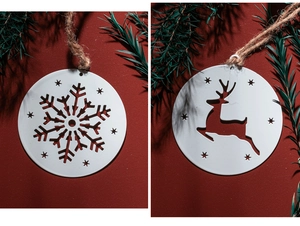 Close-up of white snowflake and reindeer metal ornaments hanging on festive pine branches