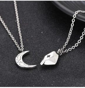 Detailed view of silver crescent moon and star pendants on a textured black surface