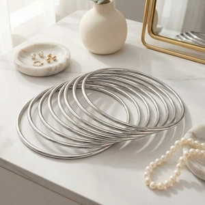 Close-up of polished 3mm stainless steel stackable bangles on white marble surface