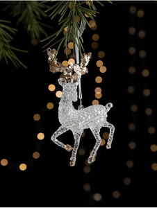 Macro shot of a clear acrylic reindeer ornament with gold glitter details on a pine branch