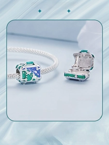 Detail of openable 925 silver suitcase charm with green and blue enamel world travel patterns