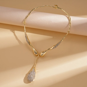 Detail of gold teardrop necklace featuring liquid metal design and sparkling rhinestones
