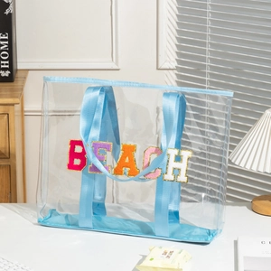 Detail of colorful BEACH chenille embroidery on transparent PVC tote with blue trim
