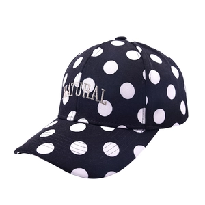 Detailed close-up of white polka dot embroidery and NATURAL text on black baseball cap
