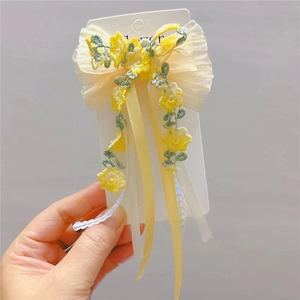 Detail of yellow flower embroidery on tulle bow hair clip with elegant long ribbons