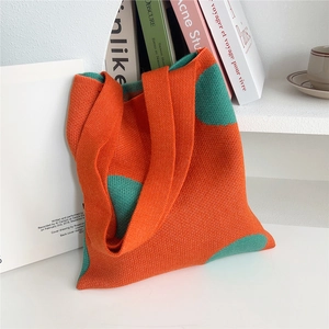 Dettaglio di una borsa chic in maglia arancione e verde posta su una libreria con libri