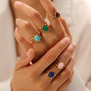Dettaglio di cinque anelli boho dorati con pietre naturali sulla mano di una modella
