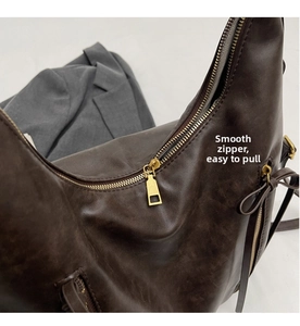 Detail of smooth gold zipper and premium brown leather texture on hobo shoulder bag