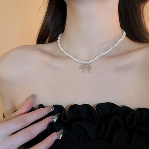 Gros plan d'un collier ras du cou en perles avec pendentif noeud argenté sur un mannequin
