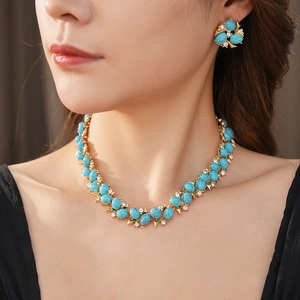 Gros plan d'un ensemble collier et boucles d'oreilles vintage en or et turquoise
