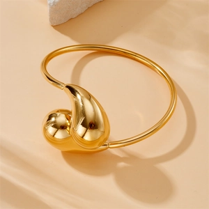 Vue détaillée d'un bracelet goutte d'eau dorée sur fond de pierre avec éclairage doux