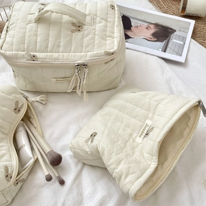 Close-up of cream quilted fabric texture and cute brown rabbit embroidery on the pouch