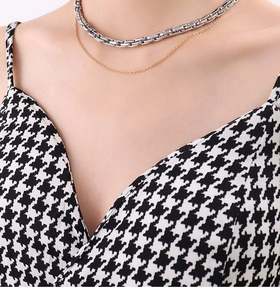 Close-up of layered gold and silver snake bone chain necklace on a model's neck