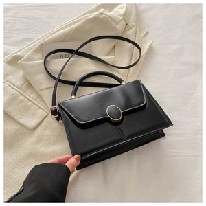 Gros plan d'un sac à bandoulière en cuir PU noir avec boucle dorée sur un blazer
