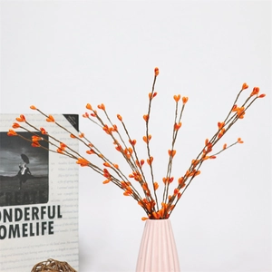 Close-up of orange artificial berries in a pink ceramic vase for festive decor