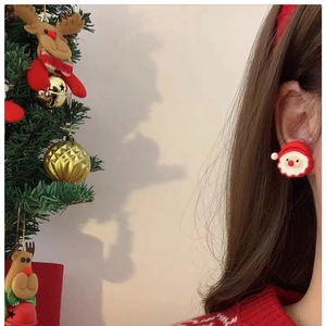 Boucles d'oreilles Père Noël mignonnes pour Noël portées par un mannequin avec sapin festif