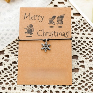 Close-up of snowflake wish bracelet on Merry Christmas card with black woven cord