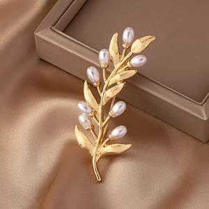Golden olive leaf brooch with white pearls on silk background, vintage elegant jewelry