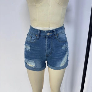Detail view of denim shorts featuring ripped texture and cuffed hems on display stand
