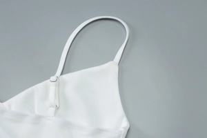 Détail de la boucle métallique et des coutures sur la bandoulière du caraco en maille blanche