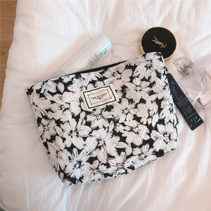 Detail of floral seersucker cosmetic bag with quilted texture and white woven label