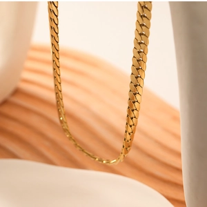 Macro view of gold snake chain necklace showing high-polished texture and link detail