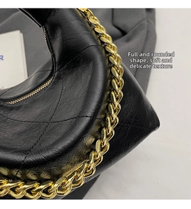 Detail shot of black quilted leather hobo bag with luxury gold chain strap