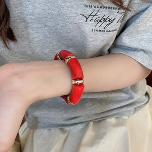 Close-up of red acetate resin bracelet with gold spacers on a model wrist for summer holiday