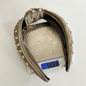 Detailed view showing an olive green satin knotted headband weighing 56.68g on a digital scale