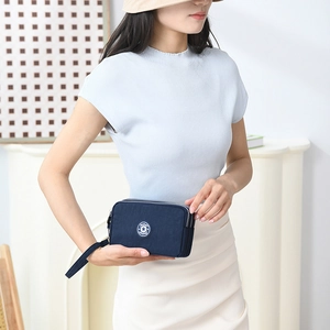 Detail van de donkerblauwe nylon mini-handtas met drie ritsen gedragen door het fotomodel