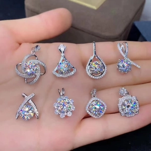 Close-up of various silver moissanite pendants held in hand with sparkling round stones