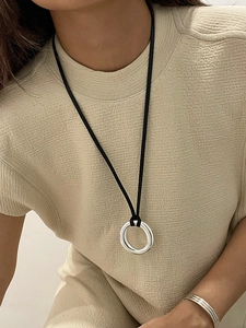 Close-up of a polished silver mirror ring pendant on a black leather cord necklace