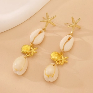 Detalle de pendientes de estrella de mar dorados con conchas blancas estilo playa