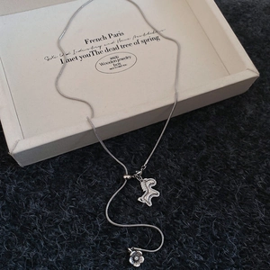 Detail of silver snake chain necklace featuring a textured pony and flower pendant