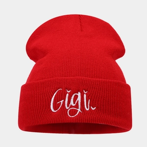 Close-up of red knitted beanie featuring detailed white Gigi embroidery on the folded cuff