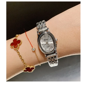 Close-up of elegant women's quartz watch with silver oval dial and metal strap on wrist